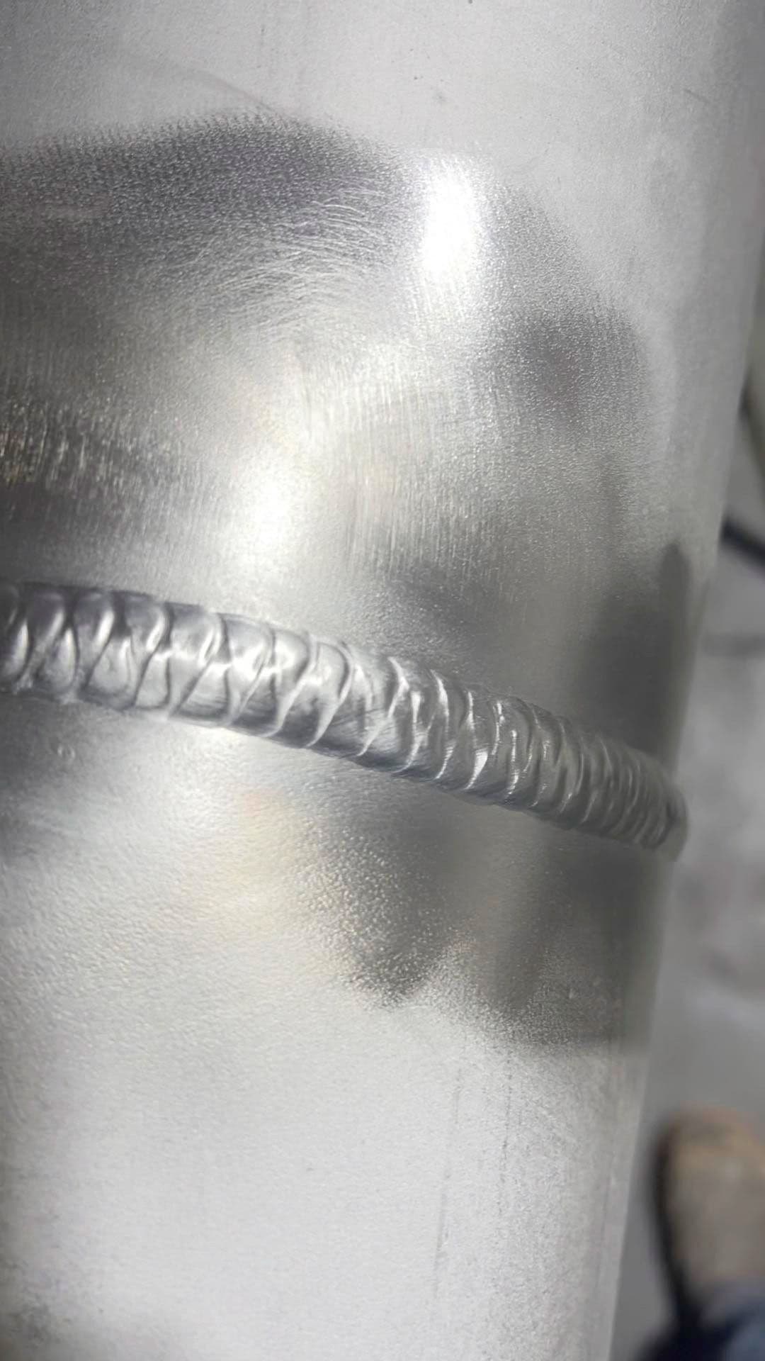 Close-up of a shiny metal pipe showcasing detailed welding seam craftsmanship.
