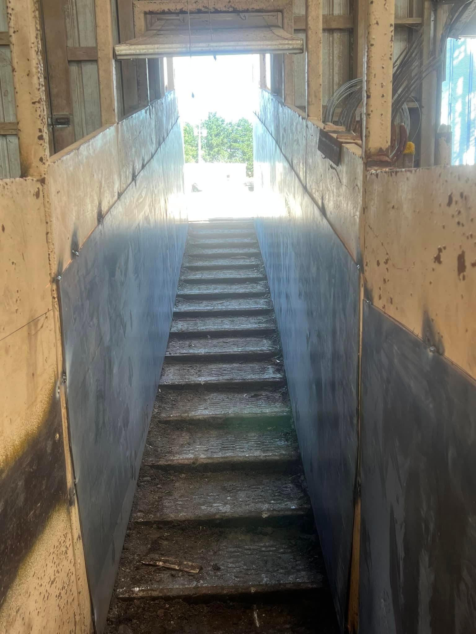 Interior view of a long, narrow staircase leading to an exit in a building.