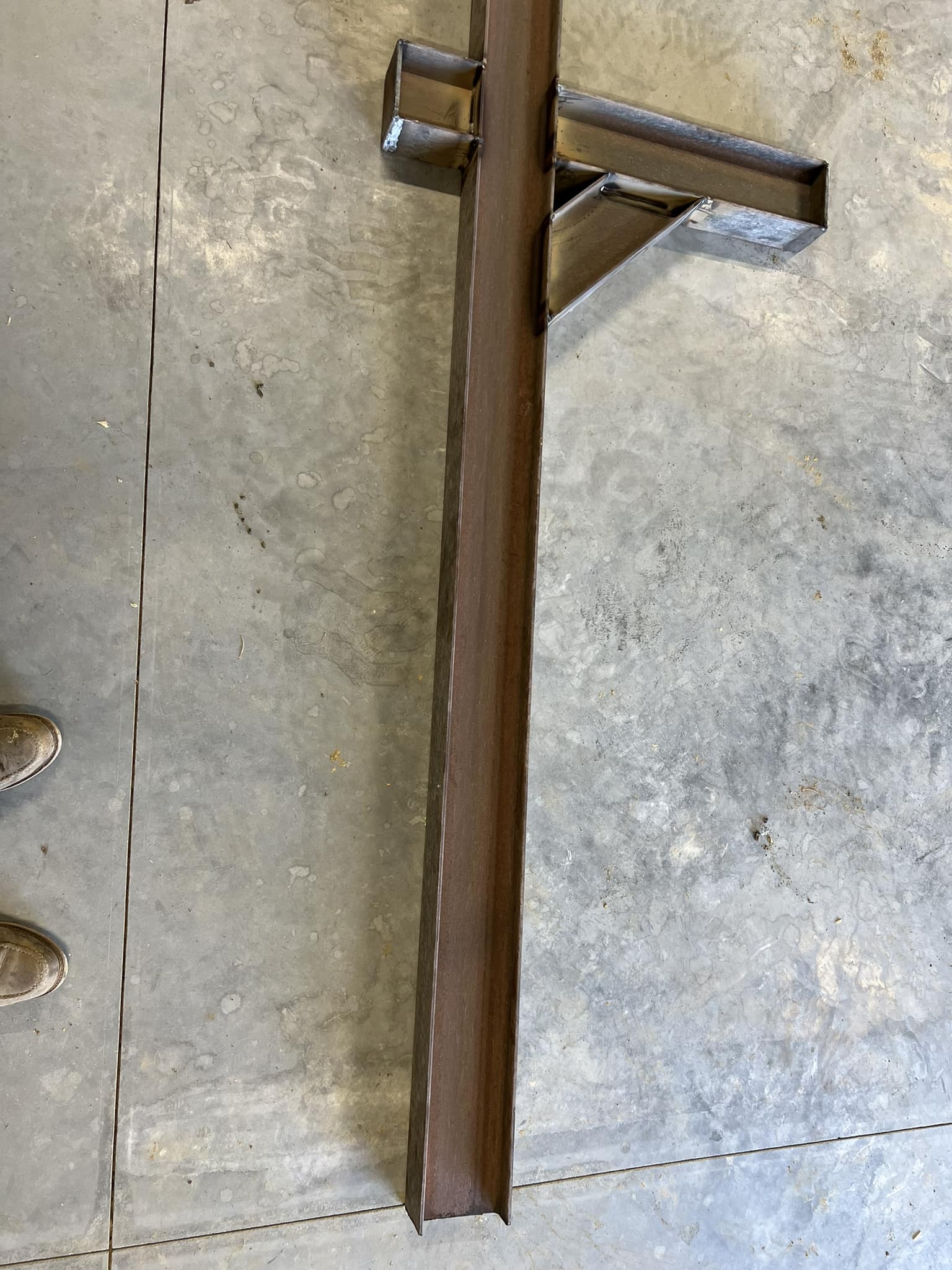 Metal beam with fabrication details on a concrete floor, showing industrial construction elements.